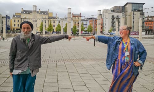 A man and a woman stand apart almost touching finger tips with outstretched arms