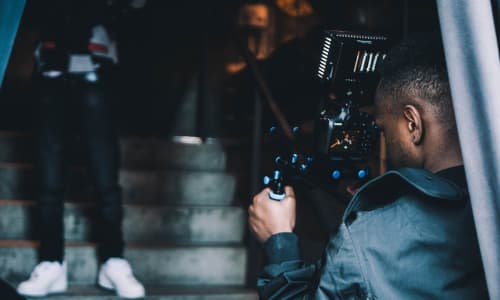 Young black man filming with a video camera