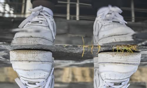 A pair of white trainers reflecting in a puddle