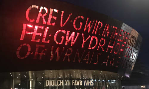 Canolfan Mileniwm Cymru wedi’i goleuo’n goch gyda’r nos