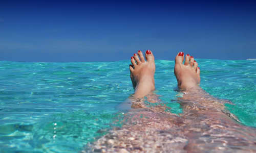 A person floating in the sea with their feet above water