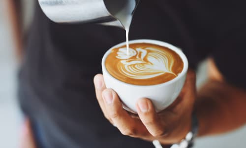 A barristo pouring a flat white coffee
