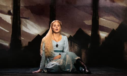 Katie Hall fel Fantine mewn ffrog las yn eistedd ar y llawr yn canu yn sioe gerdd Les Misérables. Llun: Helen Maybanks