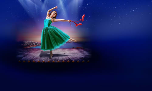 A woman in a green dress dancing barefoot, holding red shoes in her hand