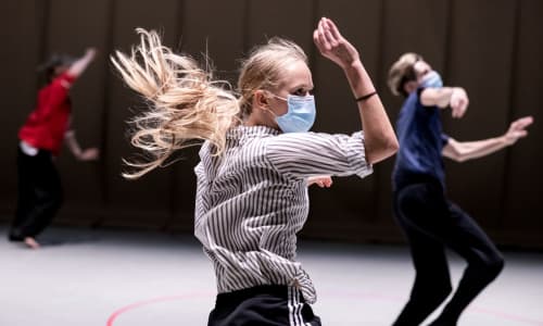 Three dancers from Rambert dancing in protective masks as they rehearse