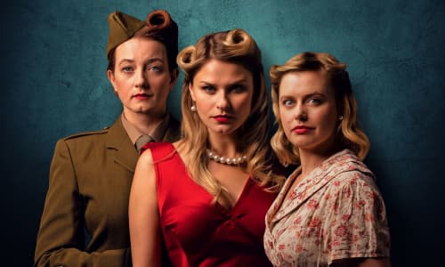 Three women dressed in period costumes from the Second World War, set against a blue background.