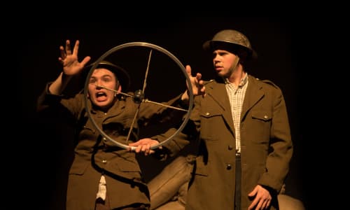 two men pretending to drive a car wearing army uniforms