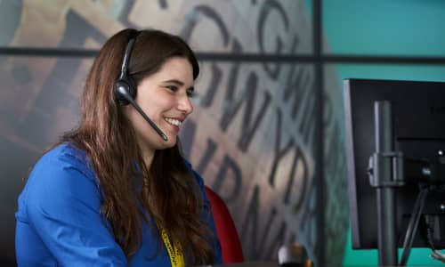 A girl with long hair smiling and speaking on the phone through a headset