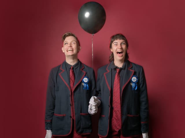 The Creepy Boys hold a black balloon.