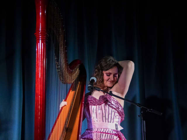 A woman playing a harp and striking a sexy pose