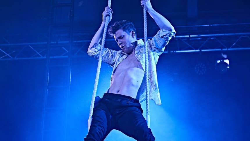 Circus artist Eric McGill stood on a trapeze with his shirt open