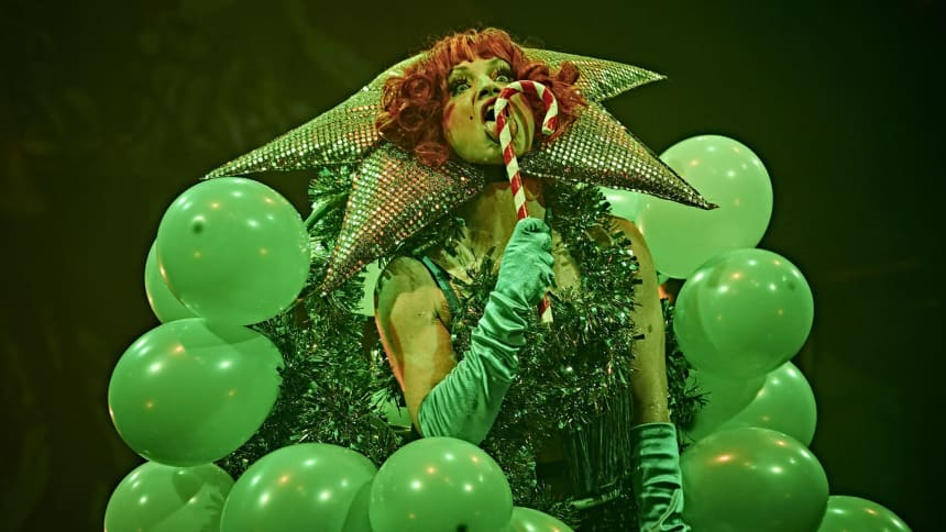 Burlesque artist Foo Foo LaBelle dressed as a Christmas tree made of green balloons licking a candy cane