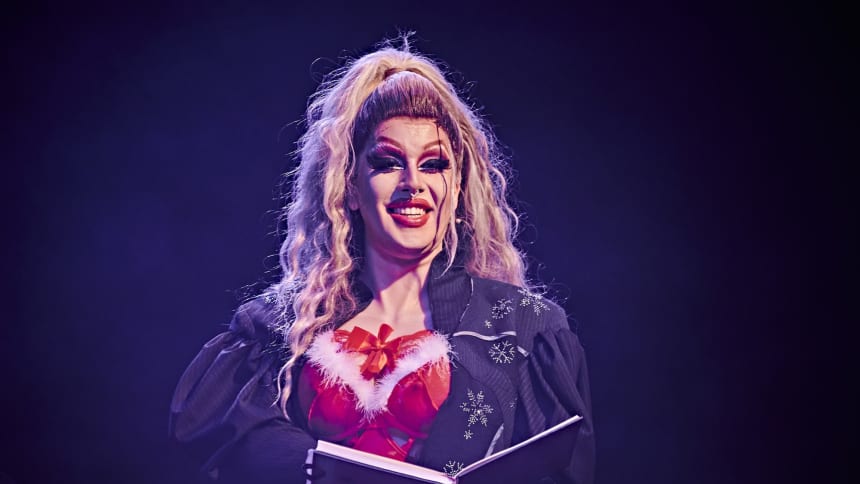 Drag Queen Polly Amorous dressed in a sexy Santa outfit, reading from a book