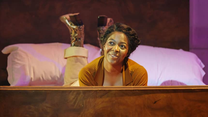 A woman lying on her front on a bed looking hopeful