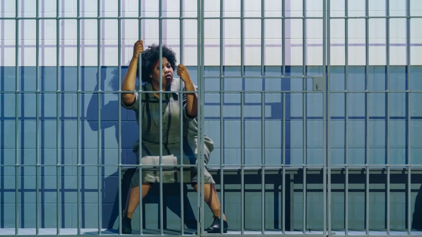 Woman seated alone behind prison bars 