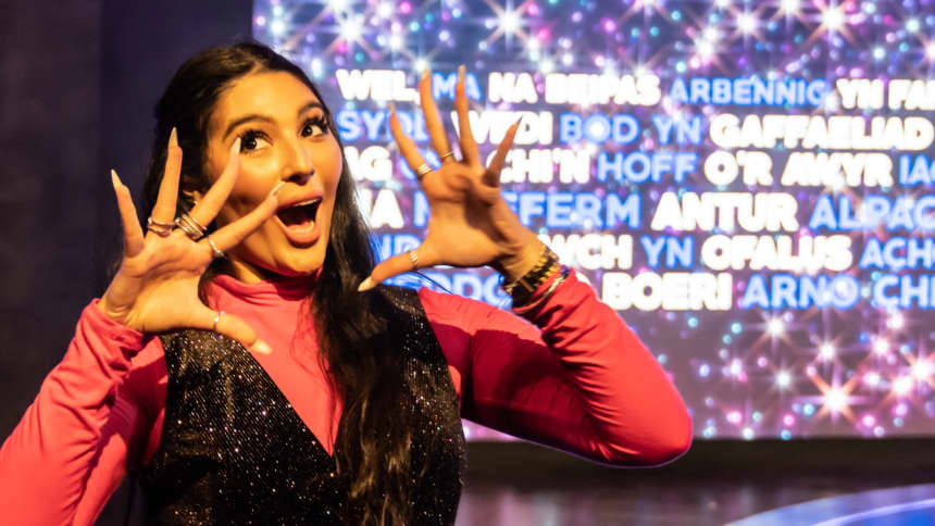 A young woman on stage in a sparkly black jumpsuit