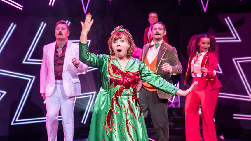 A woman dancing on stage in a green dress with a red sequinned dragon