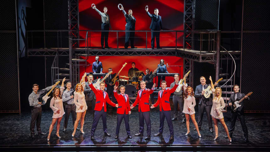 4 men in red jackets surrounded by audience cheering 