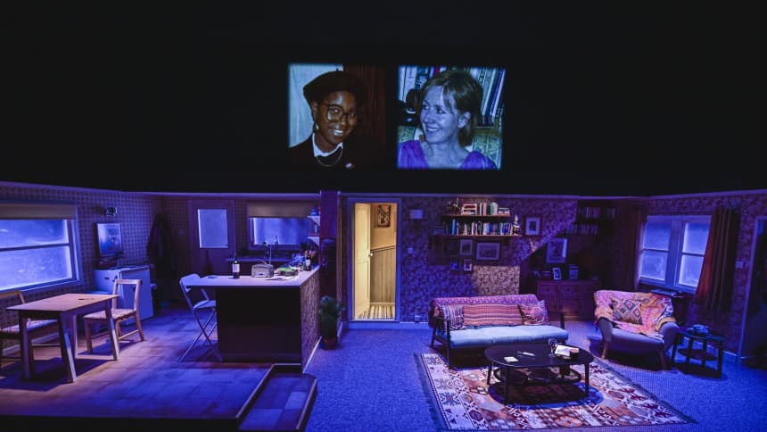 A wide shot of the Es & Flo stage which resembles the downstairs of a home, with old photographs projected above the set