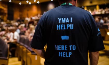 A theatre usher wearing a t-shirt that says "Yma i helpu. Here to help."