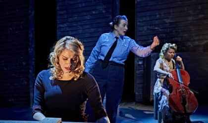 Actor Sophie Stone raising her right hand while signing against a dark background