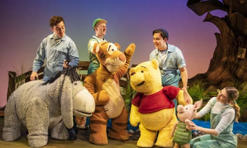 Eeyore, Tigger, Winnie the Pooh a Piglet ar y llwyfan gyda'u pypedwyr tu ôl iddyn nhw