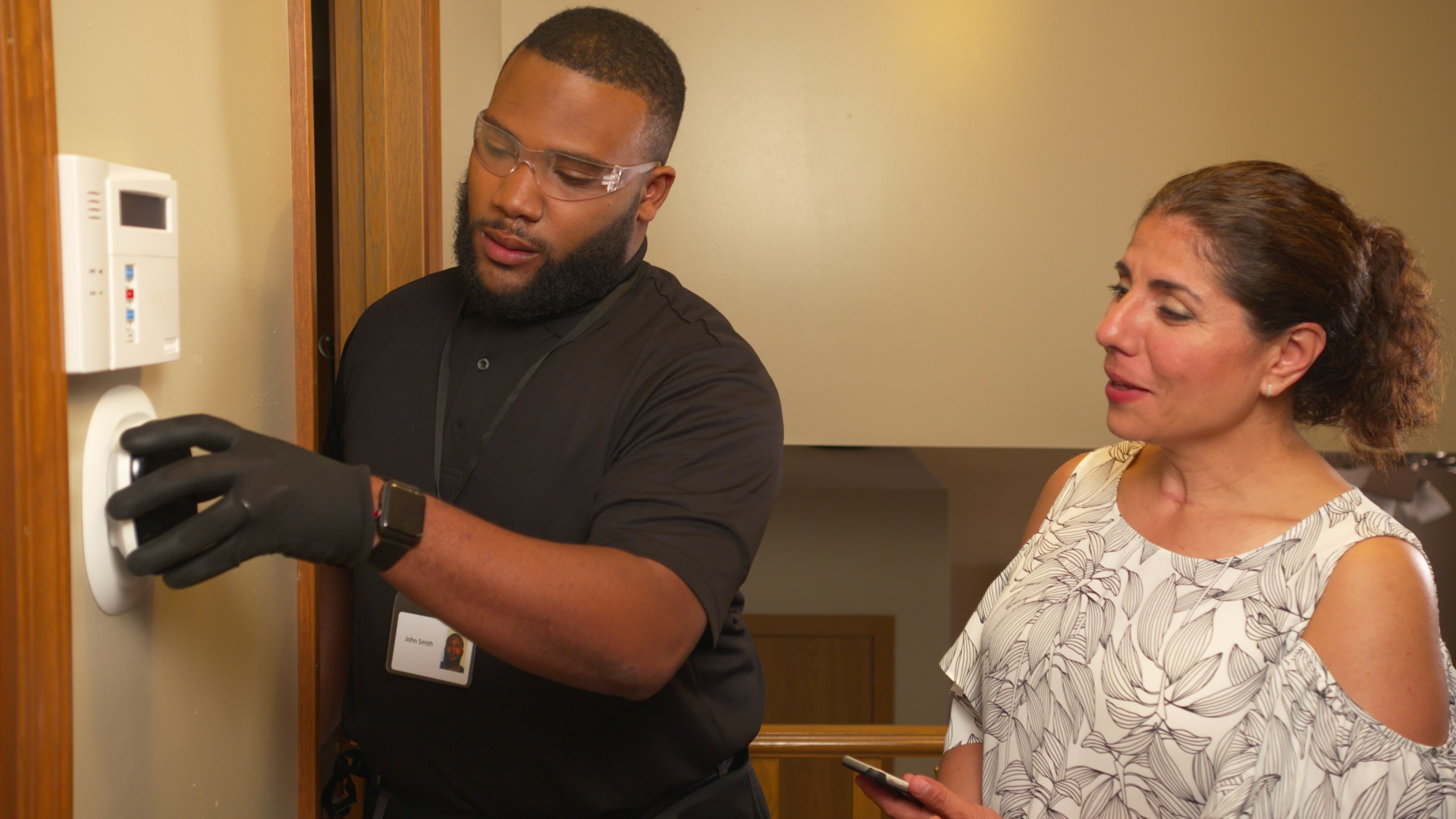 Man teaching a woman how to use a smart thermostat
