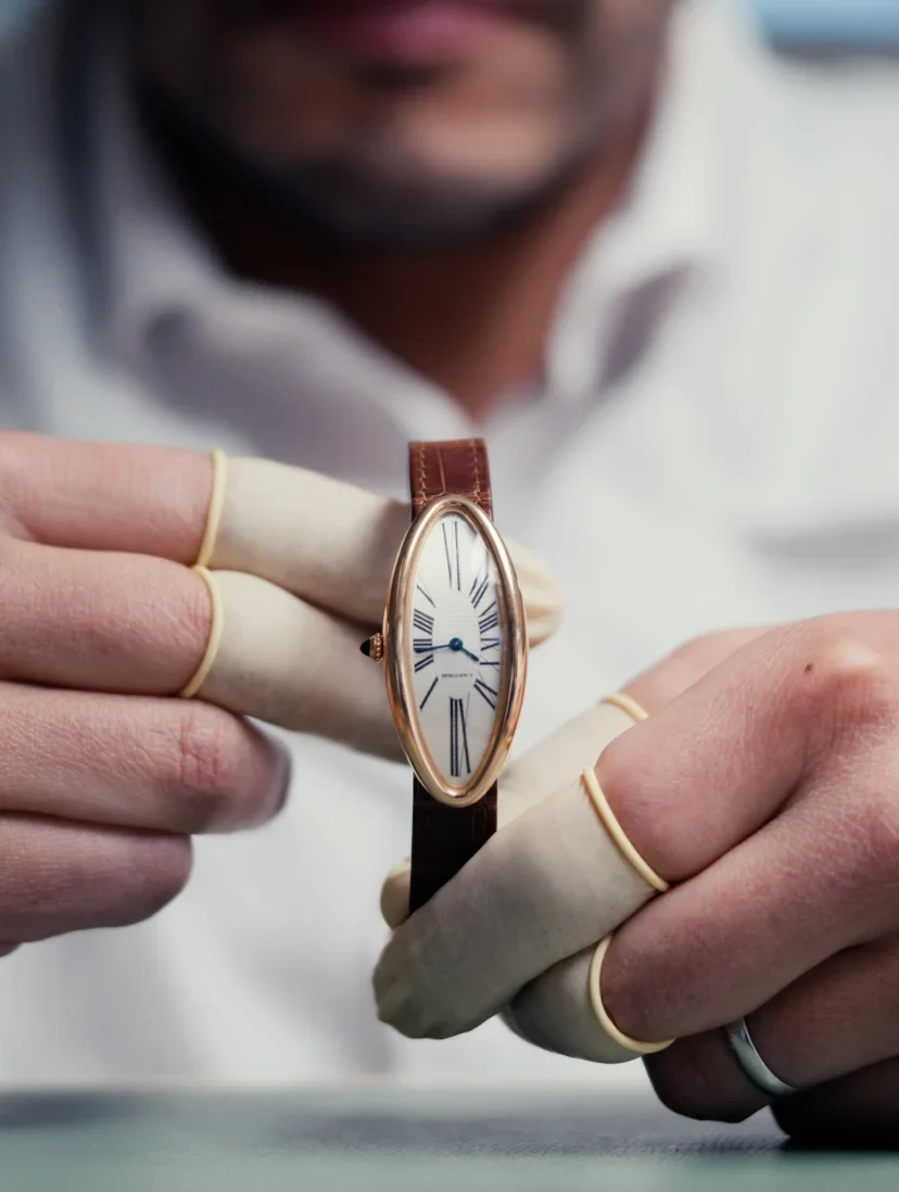 A watchmaker inspecting a movement through a loupe