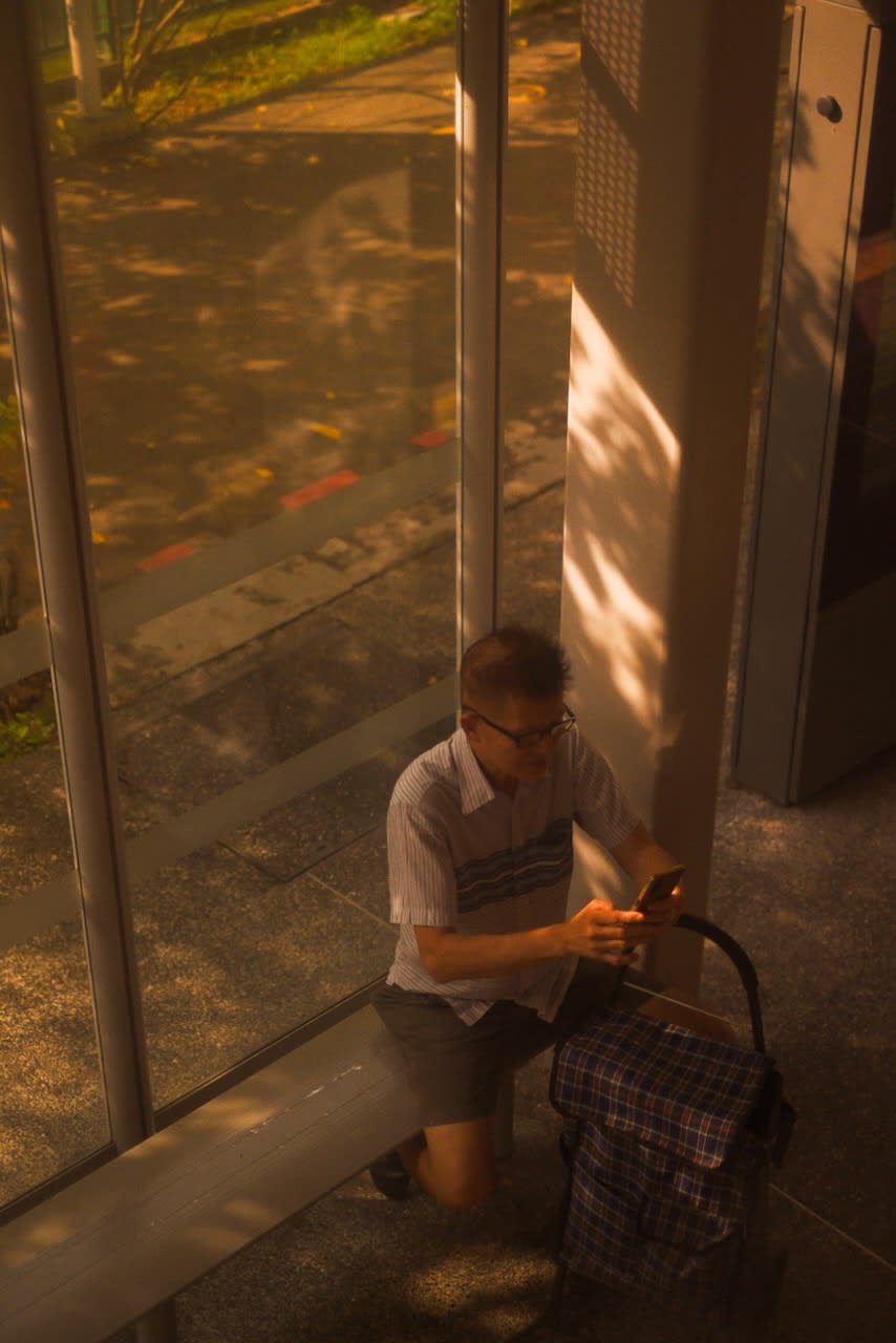 Man using his phone at a bus stop
