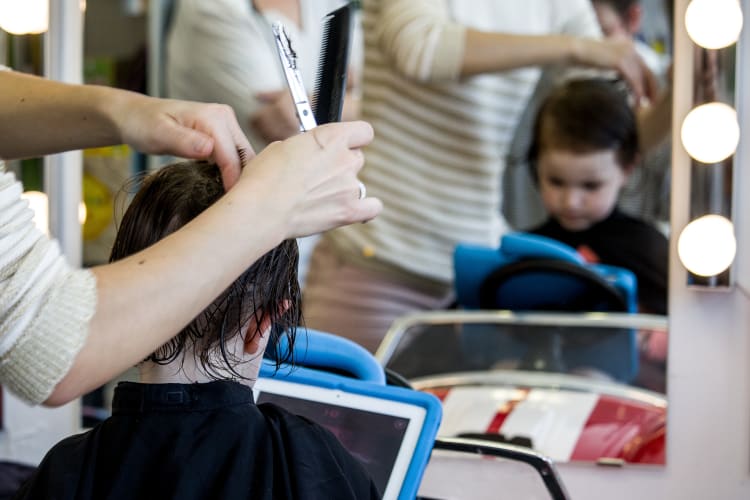 Un petit garçon entrain de se faire couper les cheveux par l'une de nos coiffeuses  