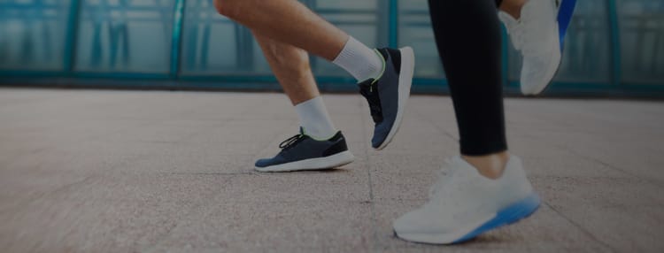 Two people running on pavement with focus on legs