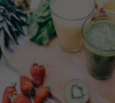 Fresh fruit and vegetables next to glasses of healthy drinks.