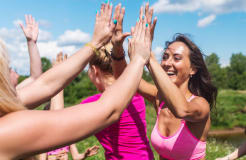A group of woman high fiving each other outside.