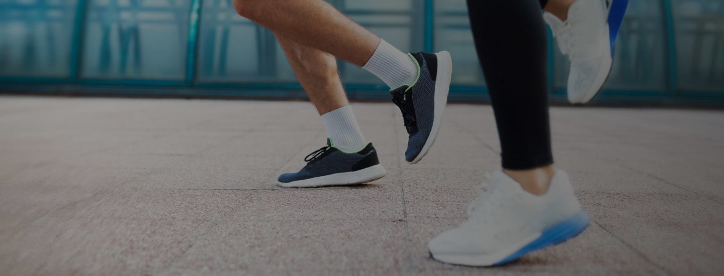 Two people running on pavement with focus on legs