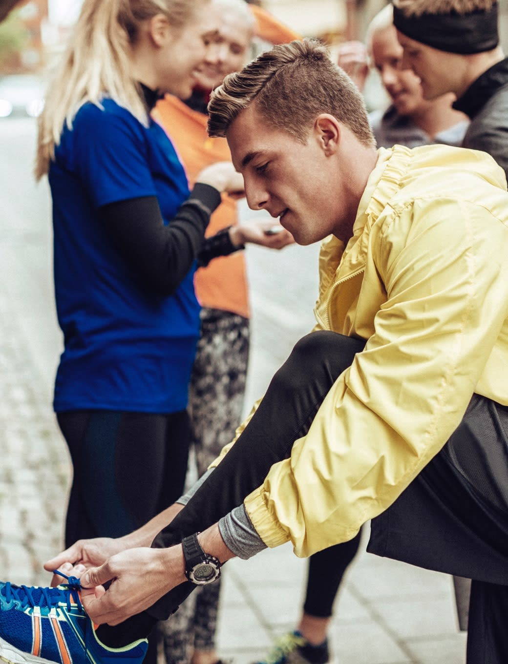 Image of a man tying his shoes before running.