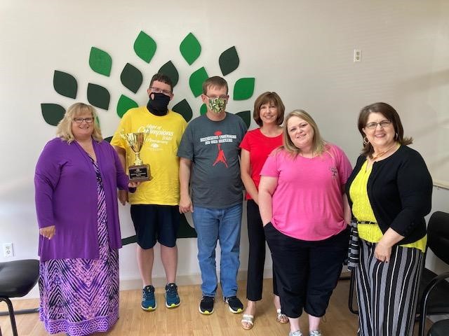 wc partners staff and champion athletes staff stand in front office area holding trophy