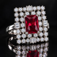 Close-up of ruby red cocktail ring featuring sparkling round and baguette-shaped CZ stones