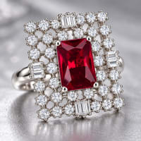 NAJEEFA ruby red CZ halo ring displayed on deep red velvet fabric