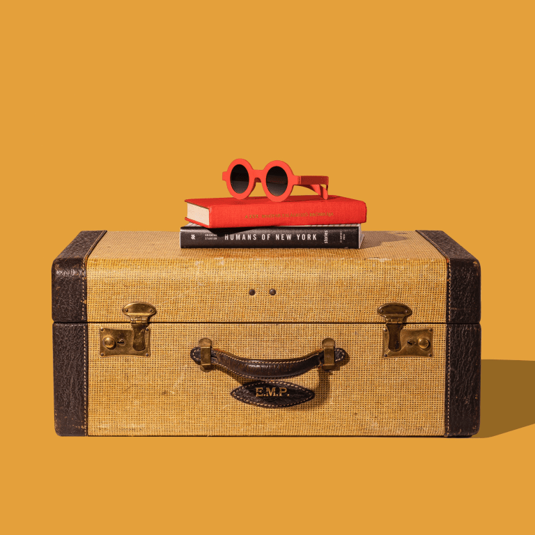 yellow vintage suitcase with Humans of New York book and sunglasses for wear to wander