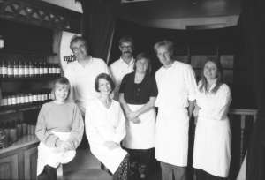 A black and white image of the 6 Lush founders and Mike Bird wearing white aprons in 1995