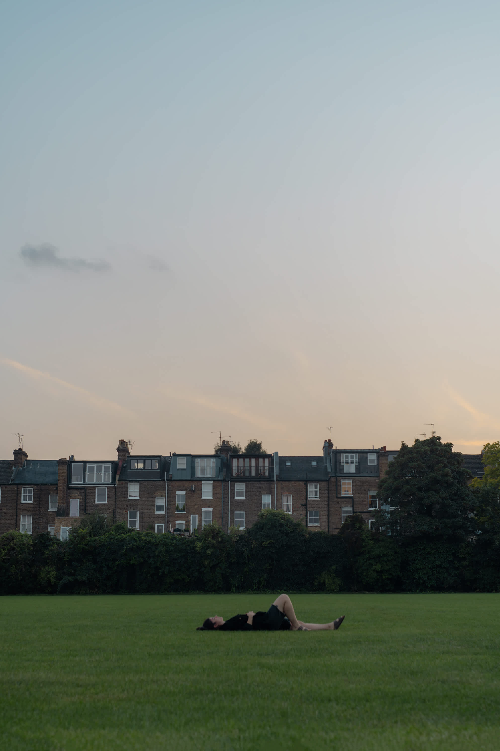 Portrait of a girl lying on the grass with houses in the background