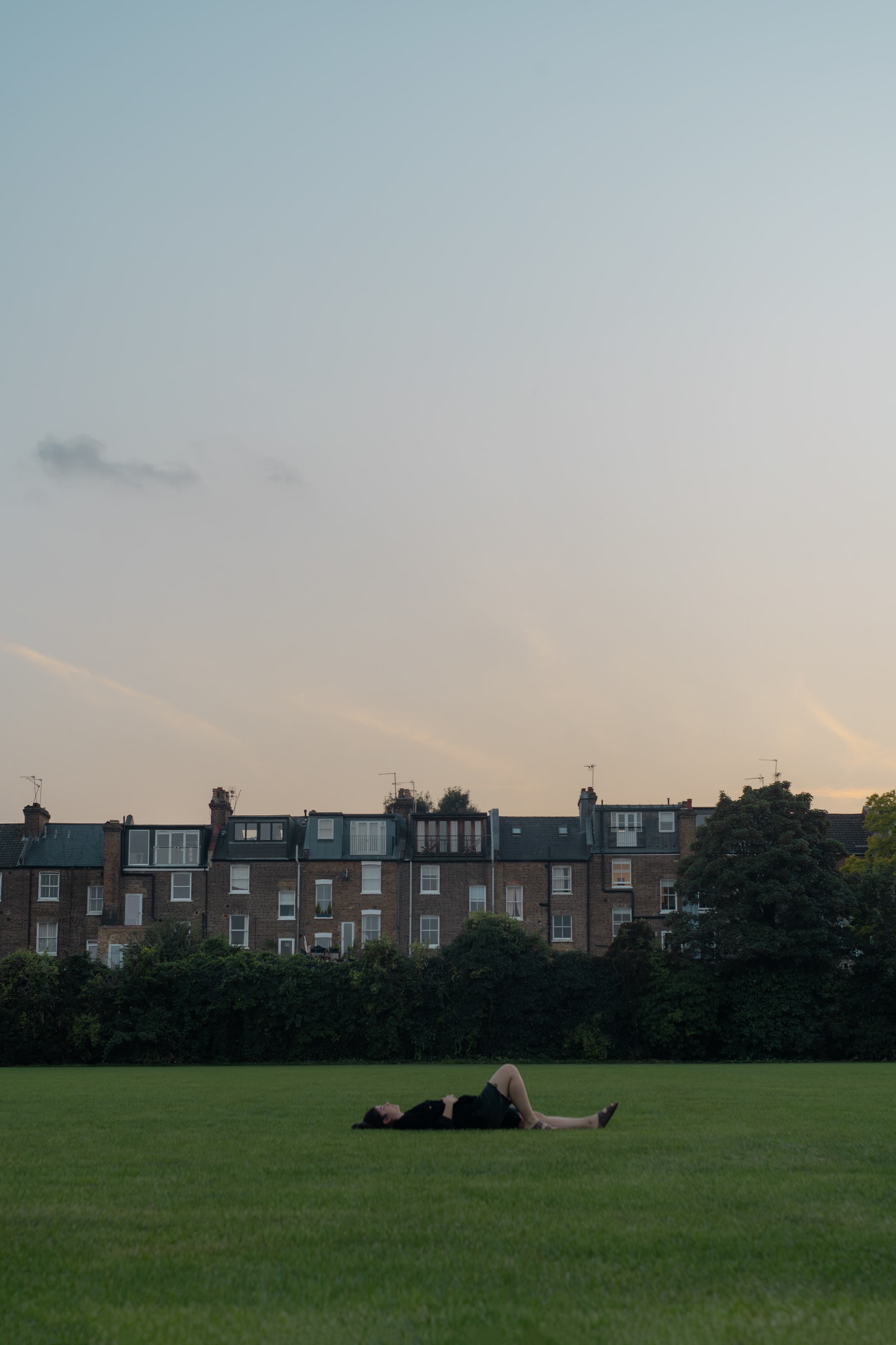 Portrait of a girl lying on the grass with houses in the background