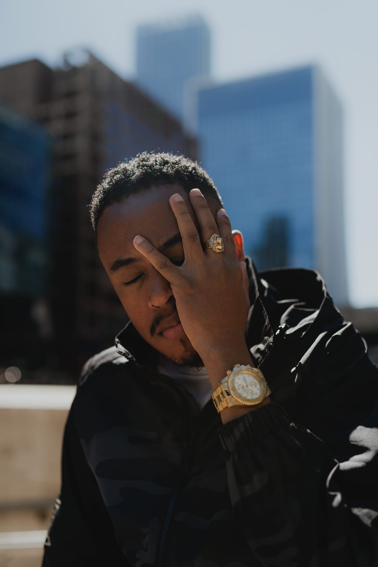 Portrait of a guy covering his face in the sunlight with his hand wearing a golden ring
