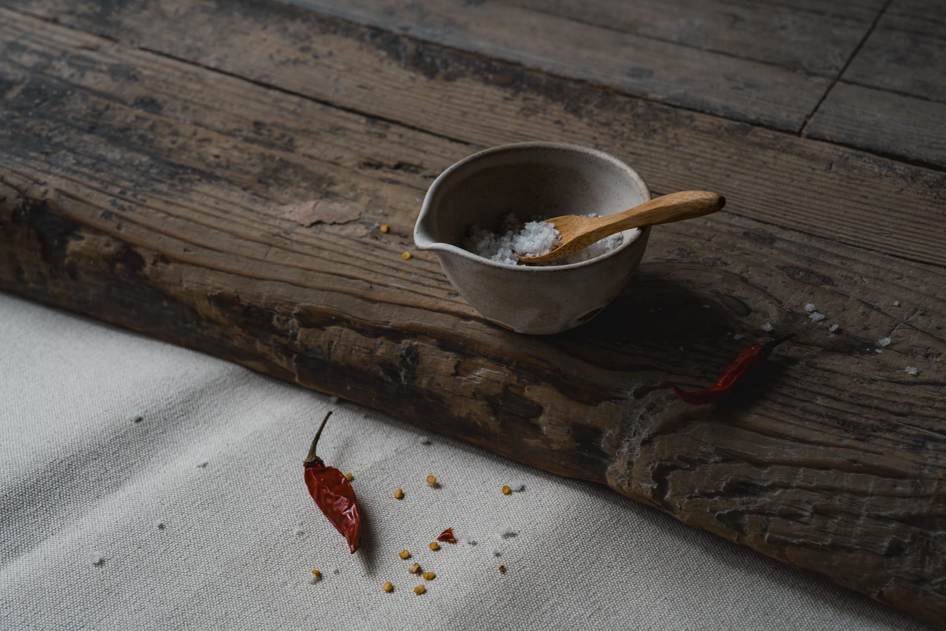 Small ceramic milk pourer and wooden tea spoon on a wooden top