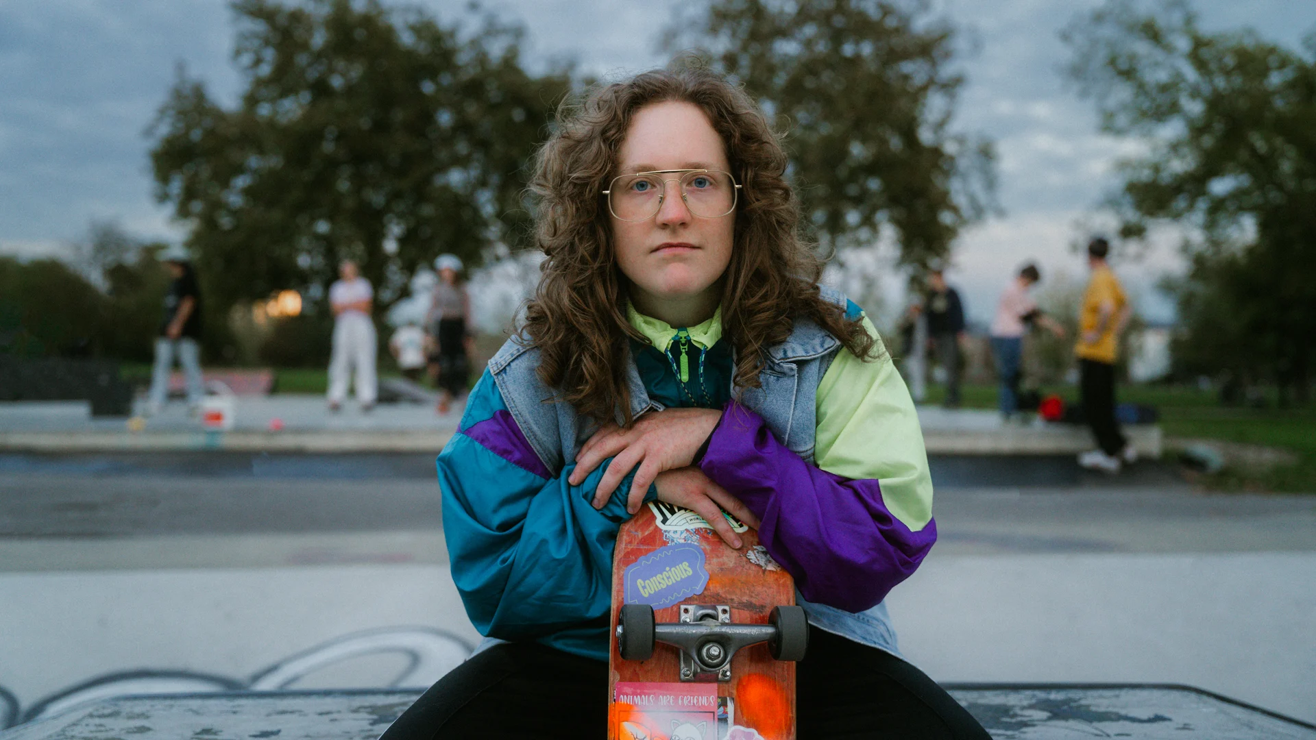 Portrait of a girl sitting on a ramp at the skate park holding her skate