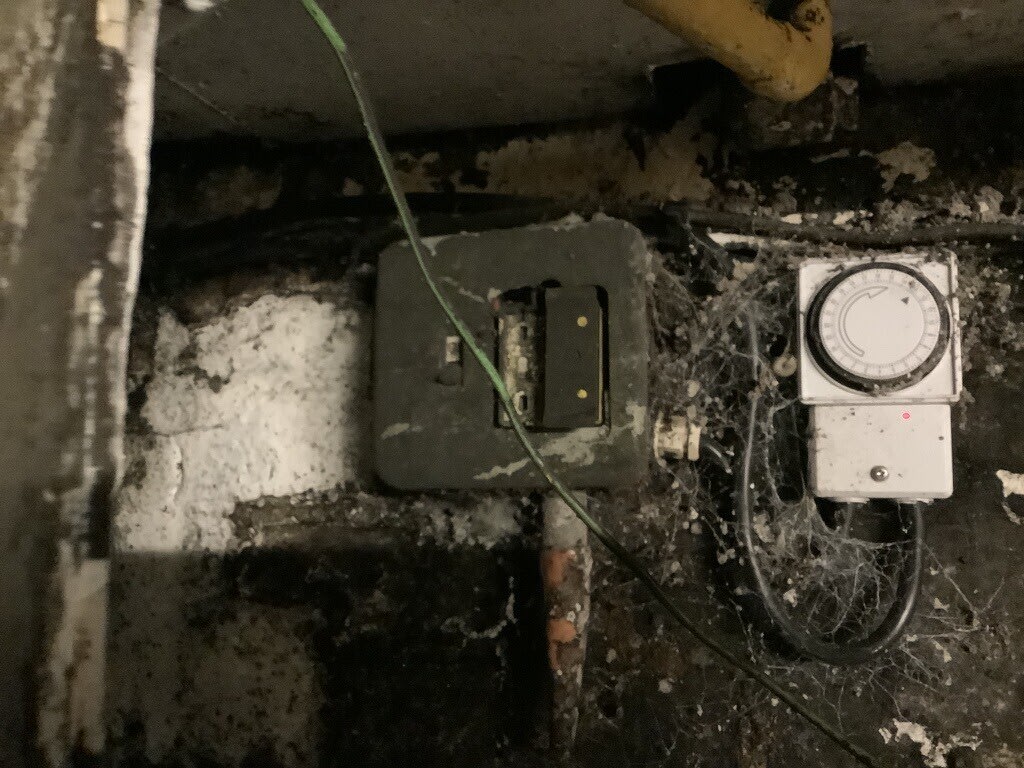 Older wall-mounted switch and timer surrounded by accumulated material at the Winchester pub