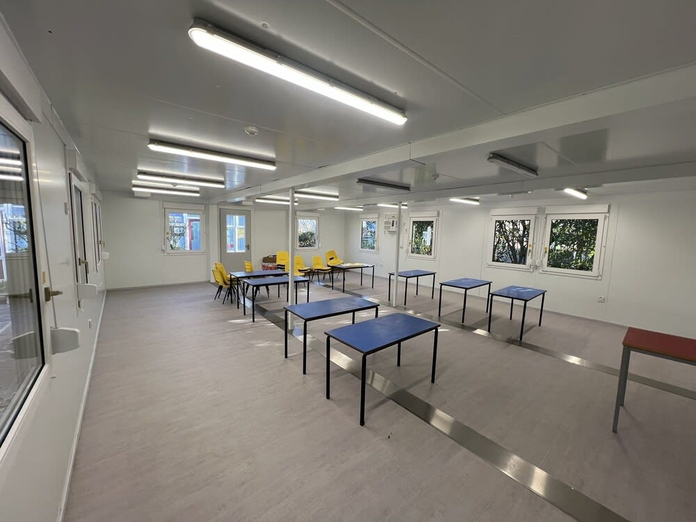 Commercial electrician installing new electrical supplies in a school classroom.