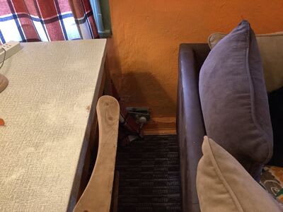 An existing electrical point behind seating, photographed before the rewire.