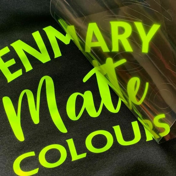 Green matte vinyl text reading “MATTE COLOURS” and “PENMARY” on black t-shirt, showcasing HTV heat transfer print finish.