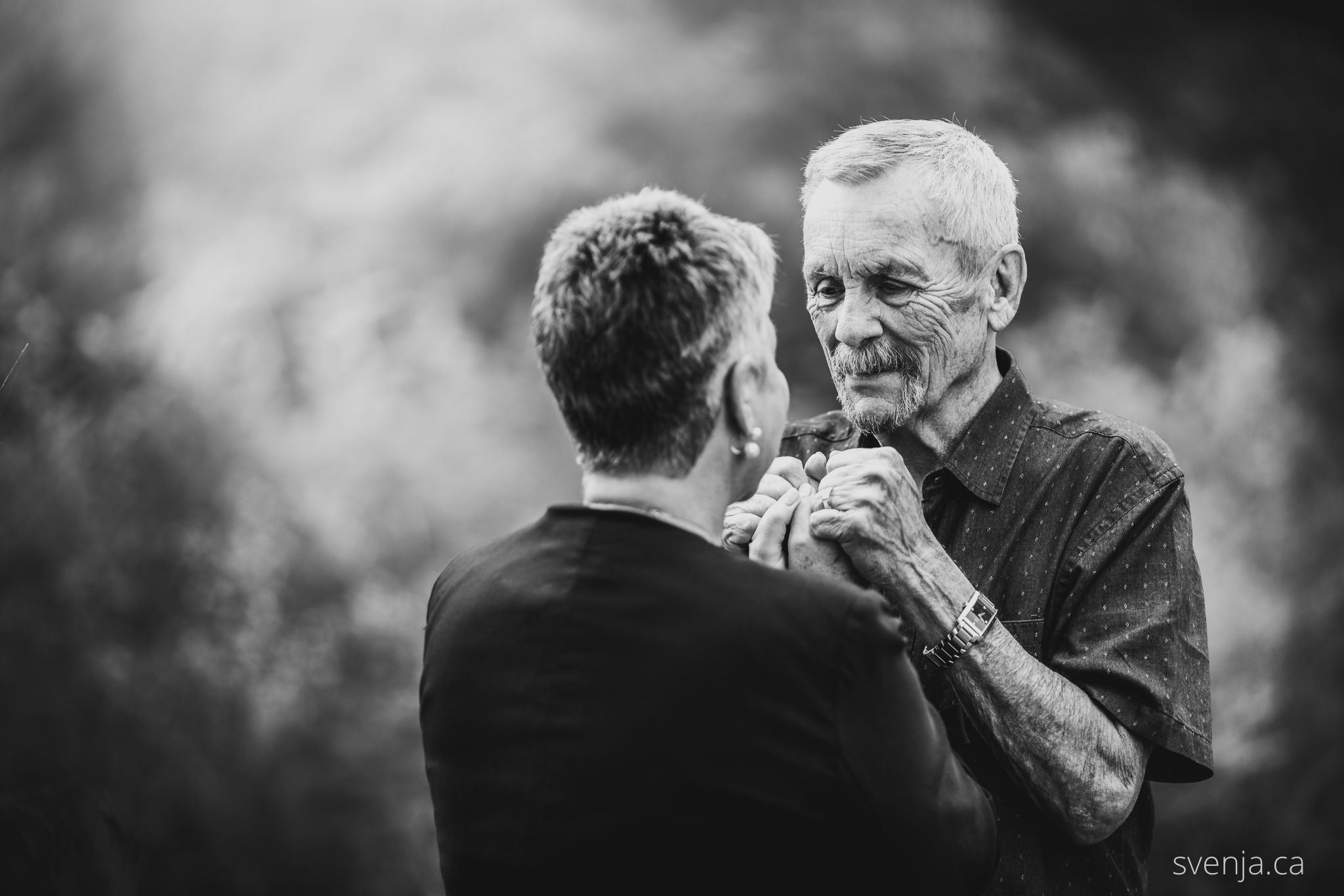 black and white photo of a man holding his wife's hands